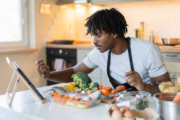 istock Man cooking at home with a recipe online 1731262020