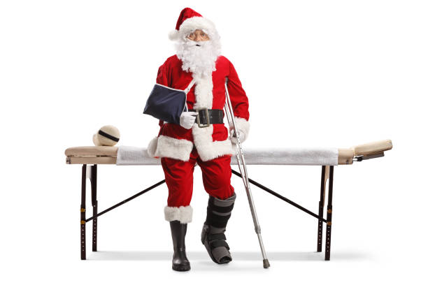 père noël avec une jambe et un bras blessés devant un lit médicalisé - christmas crutch holiday christmas decoration photos et images de collection