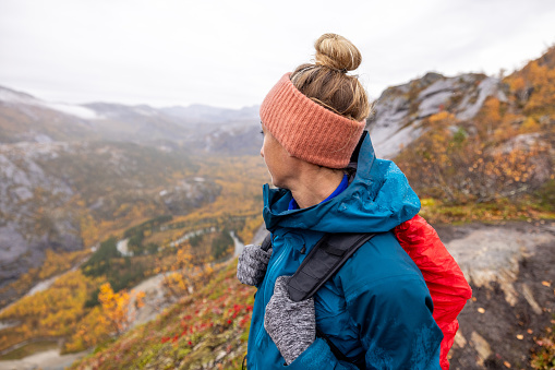 Woman hikes in the mountains of Northern Norway, she looks at the view, autumn