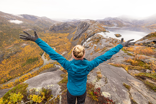 Woman hikes in the mountains of Northern Norway, she looks at the view, autumn