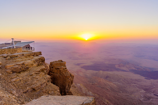 Mitzpe Ramon, Israel - August 11, 2023: Sunrise view of Makhtesh (crater) Ramon, with visitors, in the Negev Desert, Southern Israel. It is a geological landform of a large erosion cirque