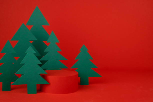 istock Christmas background - one cylinder podium, scene with 3d rendering for presentation gifts, cosmetics, goods in red color, green spruce forest, closeup. New year celebration template for advertising. 1731305810