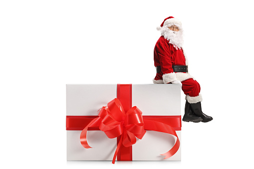 Santa Claus sitting on a big present box isolated on white background