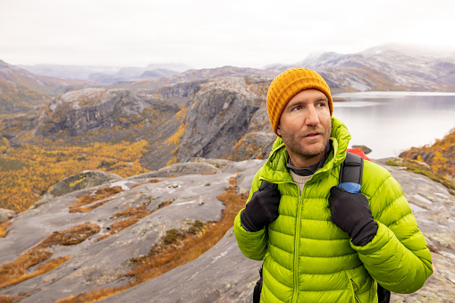 Man hikes in the mountains of Northern Norway, he looks at the view, autumn