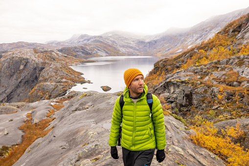 Man hikes in the mountains of Northern Norway, he looks at the view, autumn