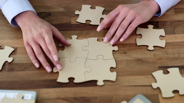 Folding pieces of puzzle hands on wooden table