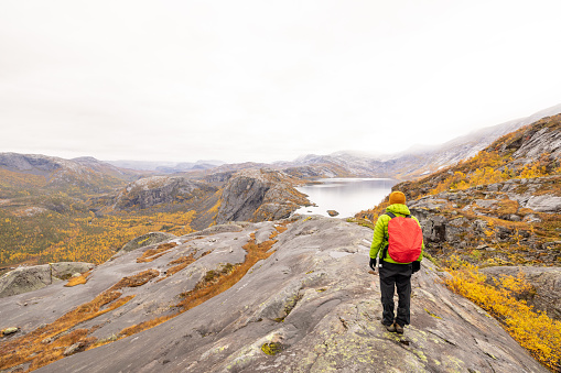 Man hikes in the mountains of Northern Norway, he looks at the view, autumn
