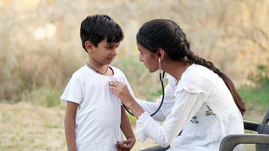 Female doctor or pediatrician with stethoscope listening to heartbeat boy's patient on medical exam at clinic. kid boy on medical examination checkup
