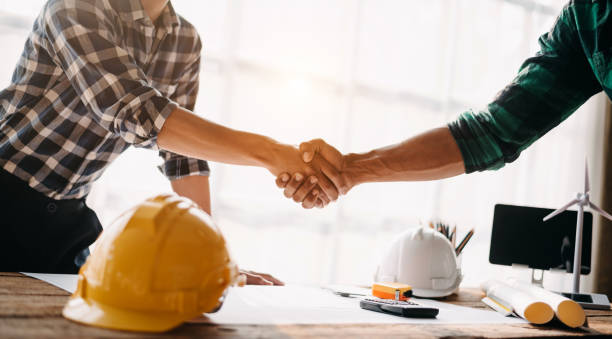 istock Construction team shake hands greeting start new project plan behind yellow helmet on desk in office center to consults about their building project. in office 1731320750