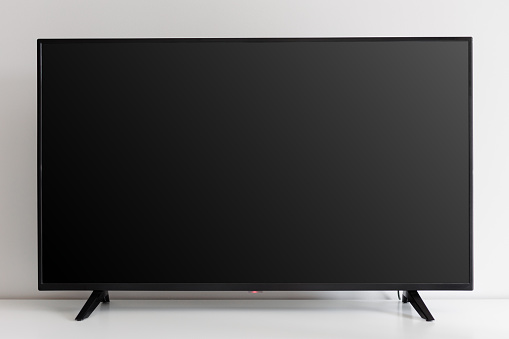 Blank black tv screen on white commode against white wall