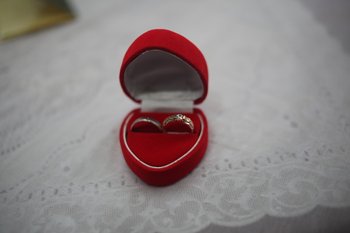 Engagement ring and wedding band in a blue velvet box held by the bride