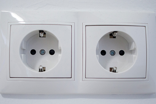 Electricity plugs in the socket on green wall