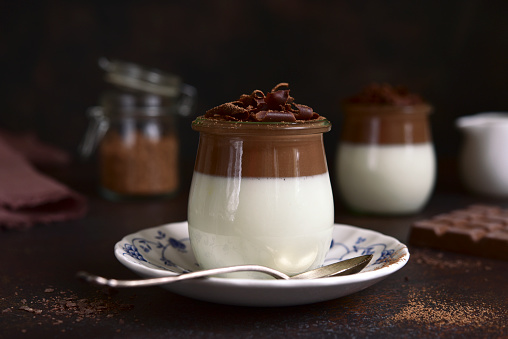 Panna cotta - traditional italian cream dessert in a vintage jars on a dark slate, stone or concrete background.