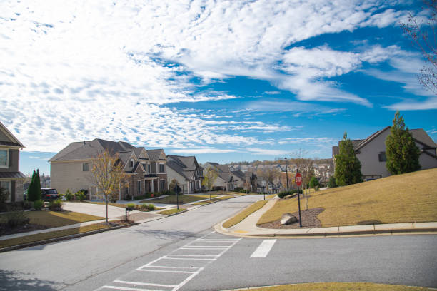 istock Three-way road intersection with stop sign, row new development suburban two story houses along street leading down steep hill near Atlanta, Georgia, USA, well-trimmed landscape 1731372416