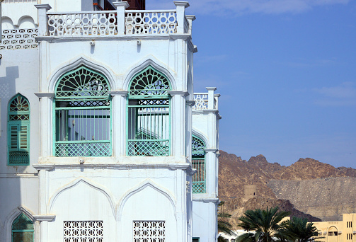 Muttrah, Muscat, Oman: detail of traditional Omani architecture on the corniche, Al Bahri Road - waterfront building with terraces and oriental verandas - Al Hajra mountains in the background.
