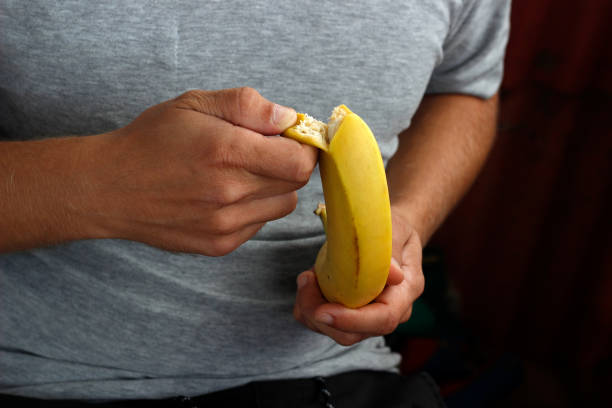 istock banana in hand, man peeling banana 1731400403