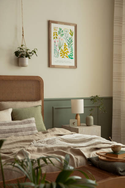 Cozy composition of bedroom interior with mock up poster frame, stylish bed, beige bedding, lamp, plants in pots, vase with leaves, wall with stucco and personal accessories. Home decor. Template. acogedora composición del interior del dormitorio con marco de póster de maqueta, cama elegante, ropa de cama beige, lámpara, plantas en macetas, jarrón con hojas, pared con estuco y accesorios personales. decoración del hogar. plantilla.
