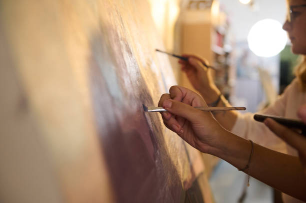 istock Details on artist's hands work on painting on canvas, in creative art studio, holding palette with oil paints and brush 1731438388