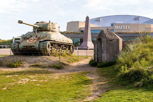 Sainte-Marie-du-Mont, France - Sept. 6, 2023: M4 Sherman medium tank and monument to the 4th Infantry Division of the US Army in front of the Utah Beach Landing Museum dedicated to D Day.