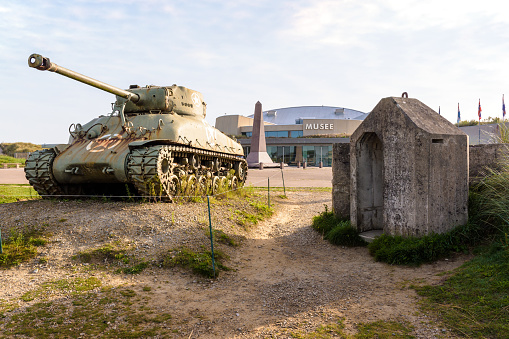 Sainte-Marie-du-Mont, France - Sept. 6, 2023: M4 Sherman medium tank and monument to the 4th Infantry Division of the US Army in front of the Utah Beach Landing Museum dedicated to D Day.
