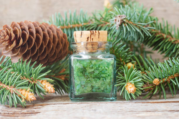 istock Small bottle with green aroma bath salts (foot soak) with coniferous tree extract. Christmas aromatherapy. Winter spa and herbal medicine concept. Old wooden background. 1731447134