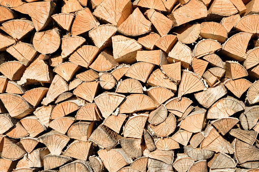 firewood wooden row as background or pattern. Background of stacked chopped wood logs. Pile of wood logs ready for winter. Wooden stumps, firewood stacked in heap