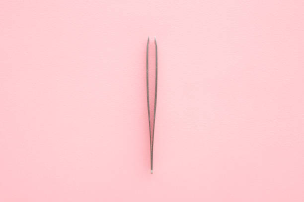 istock Tweezers on light pink table background. Pastel color. Closeup. Top down view. 1731460255