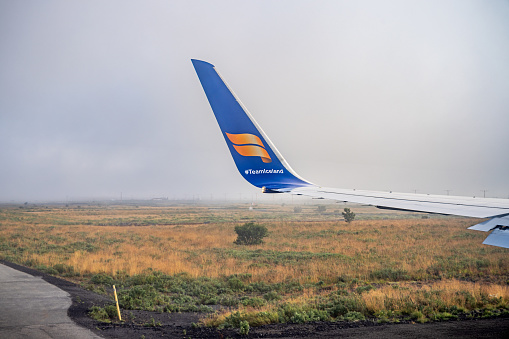 Keflavik, Iceland - August 24th 2023:  Winglet of a Boeing 757-300 with Iceland Airs logo over Iceland over the grass and moss covered Icelandic landscape while taxing on the ground