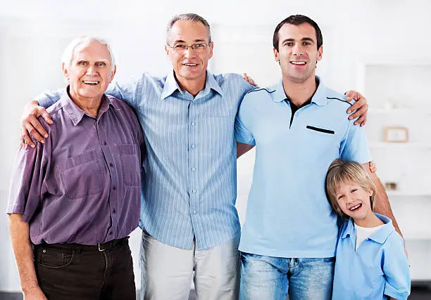 Adult son, father, grandfather and grandson embraced looking at the camera.   