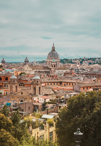 View of the streets of Rome near the Spanish Steps, from the heights of Villa Borghese Park. Famous place of the historical city. Italian cityscape. Vertical travel photo.