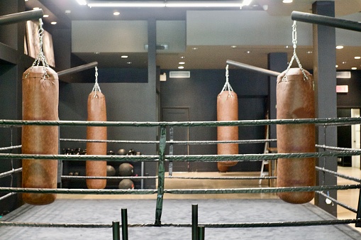 A boxing ring with heavy bags as the centre piece of a gym.