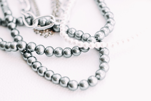 A necklace of gray beads with chain decorations on a white aesthetic background.