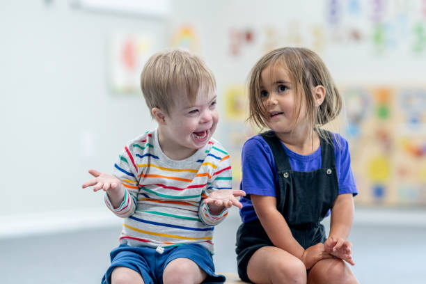 Preschool Portrait Two preschool aged children sit on a small wooden bridge as they pose together for a portrait. They are both dressed casually and are smiling. special needs child pictures stock pictures, royalty-free photos & images
