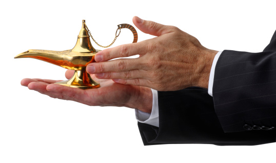 A businessman holding and rubbing a magic lamp.