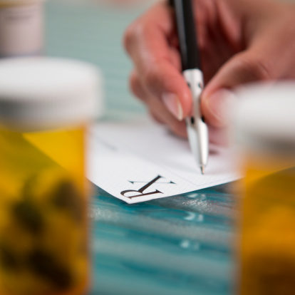 Closeup of pharmacist filling out prescription RX.