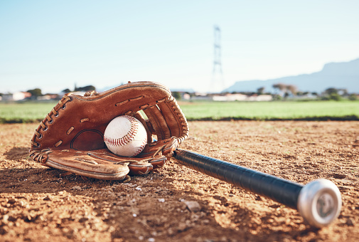 Glove, bat and baseball gear on the sand for a game, professional competition or sports. Ground, fitness and equipment for a match, fitness or training for softball on the sand in summer for cardio