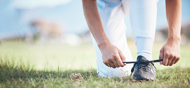 Hands, feet and a sports person tying laces on a baseball field outdoor with mockup space for fitness. Exercise, shoes and getting ready with an athlete on a pitch for a match or training closeup
