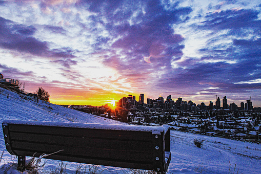 Snowy sunrise over downtown Calgary with a bench in the foreground