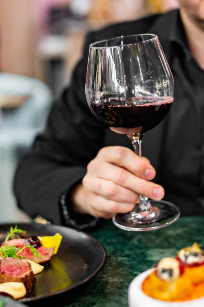 istock Young man hand holding a glass with red wine in a restaurant 1731577953