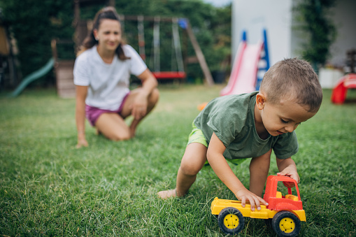 Mother with her little son who is playing in back yard outdoors.