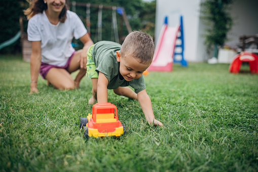 Mother with her little son who is playing in back yard outdoors.