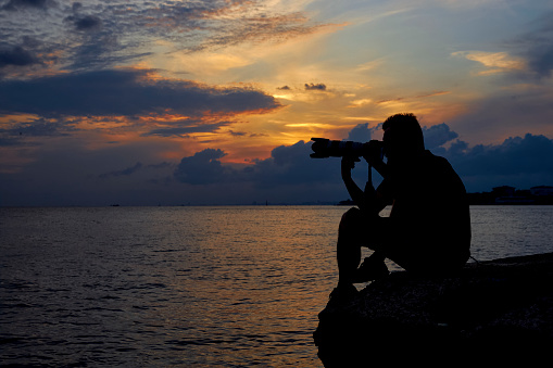 silhouette of a male photographer with tele lens and dramatic sky