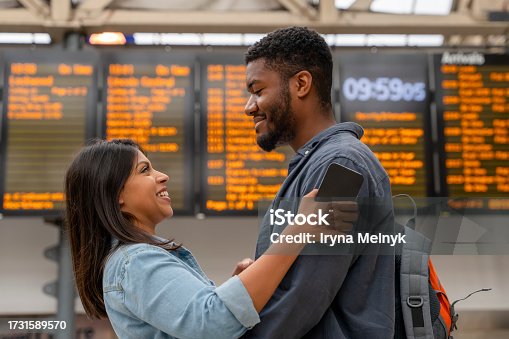 istock young family couple at the train station exited about oncoming travel in front of timetable Passengers traveling,  journey concep 1731589570