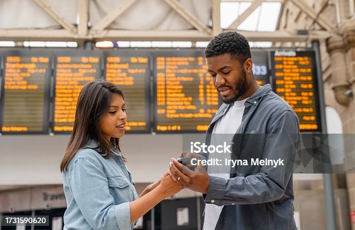 istock young family couple at the train station exited about oncoming travel in front of timetable Passengers traveling,  journey concep 1731590620