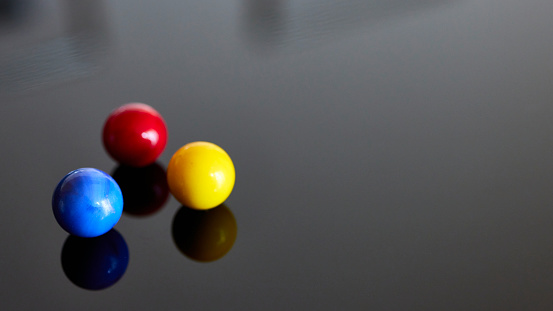 Three pool balls, blue, red, yellow, on black background