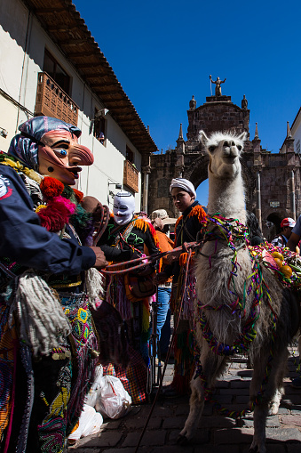 Corpus Christi celebration: masked people and llama gathered for the traditional parade in the streets of Cusco