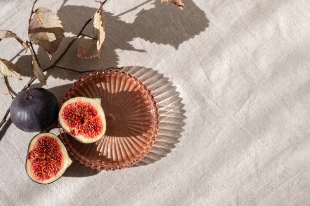 Figs fruits half cut in golden bowl on luxury gold background with copy space and leaves shadows