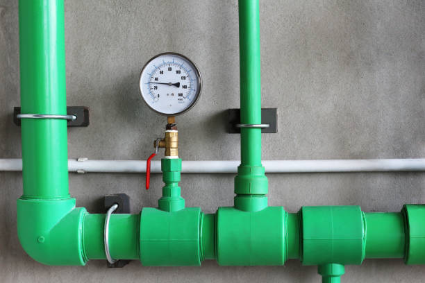 Water pressure gauge with valve in pipe on concrete wall background. stock photo