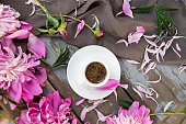 Pink peony flowers and a cup of coffee on a white background. Morninig, spring, fashion composition. Flat lay, top view, copy space.
