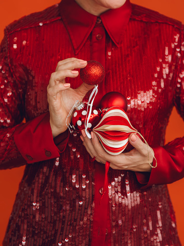 Woman holding christmas decoration ornaments in red sequin shirt
Photos taken in studio